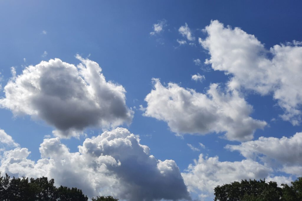 Dichte, flauschige Wolken am Himmel. Ich glaube, man nennt dieses Wolkengebilde Kumuluswolken.